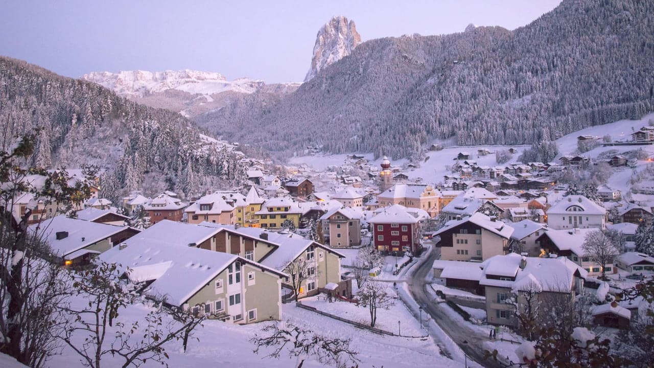 Aerial view of a snow covered mountain village beneath a peak, no people in frame