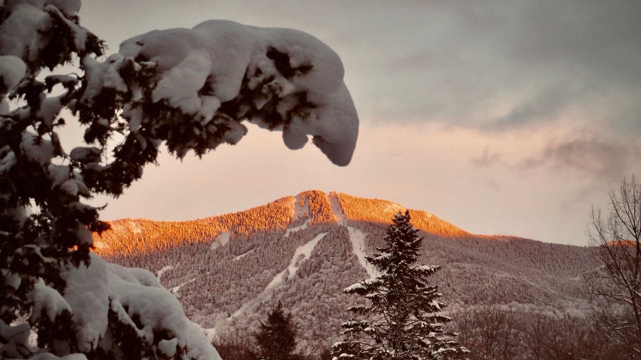 Snow covered Dolomite peaks glowing orange and pink at dusk