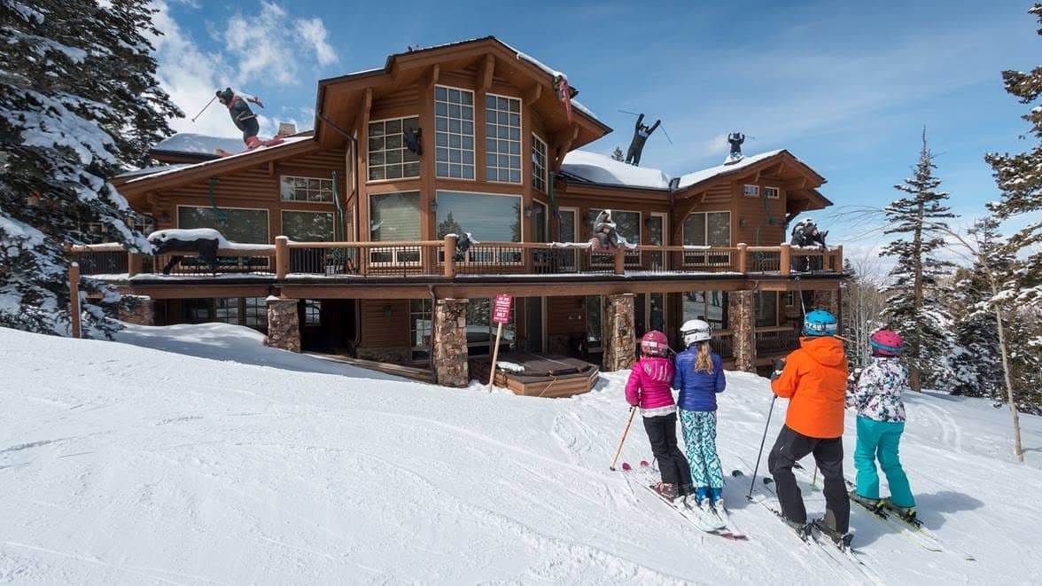 A family on skis in front of a timber lodge at Deer Valley