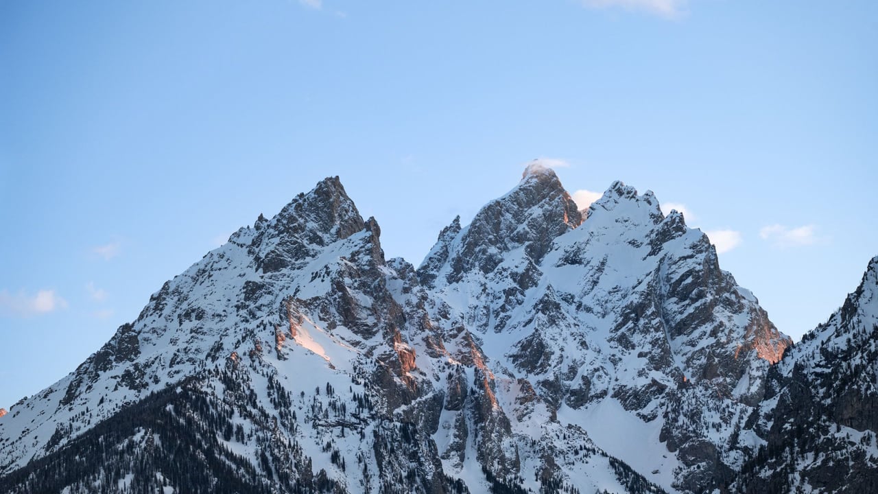 Jagged snow covered twin peaks rising against a clear blue sky, no people in view