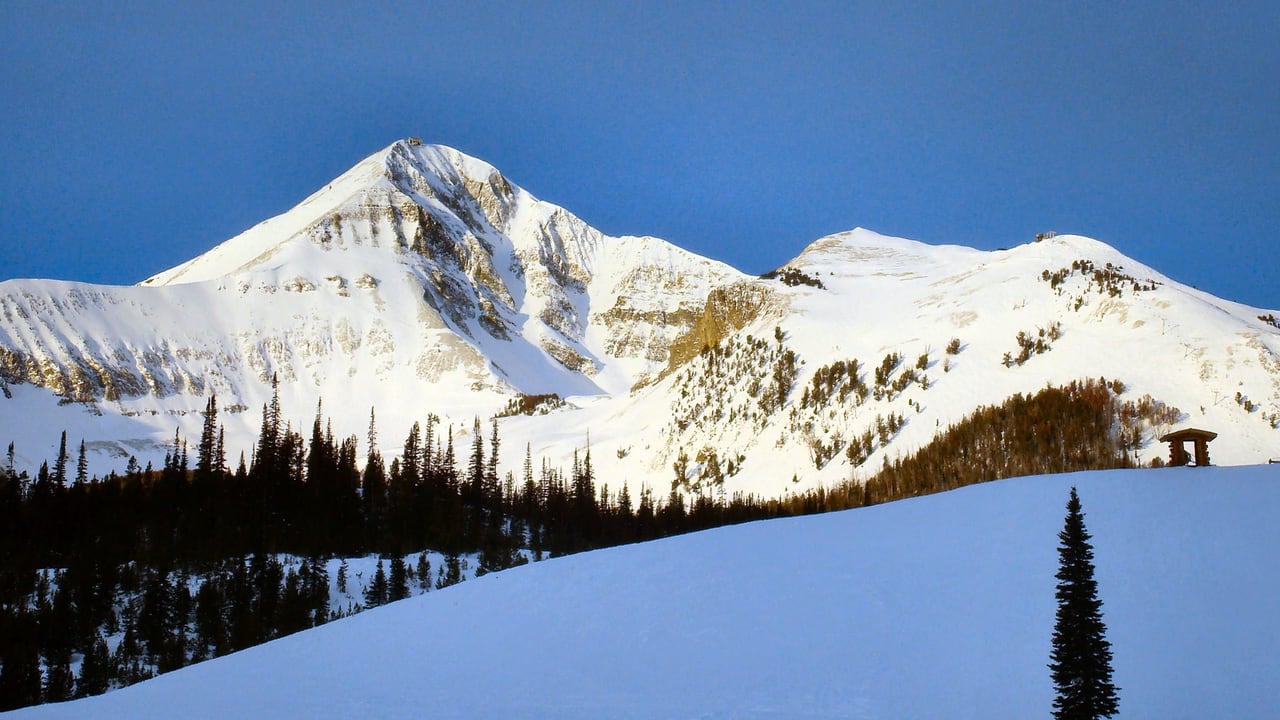 Clear sky over fresh snow on an open mountain, no one on the slope yet