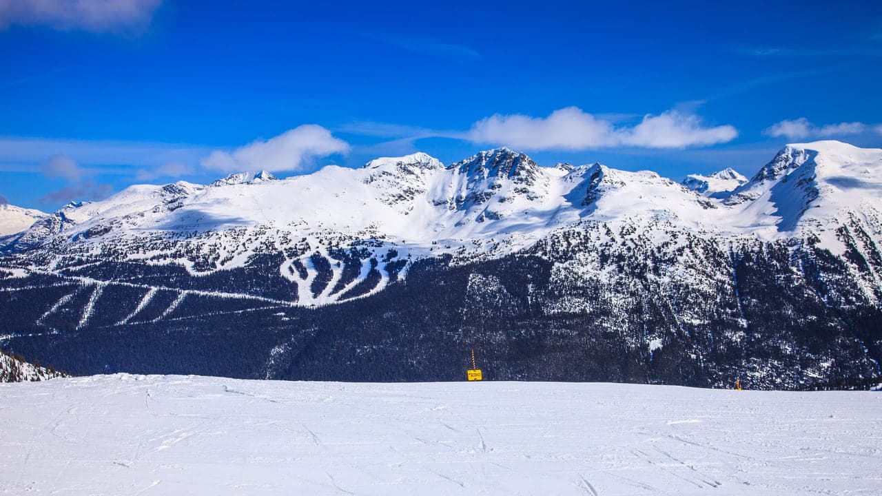 Aerial view of a snow covered ski resort beneath clear peaks, slopes empty in the early morning light