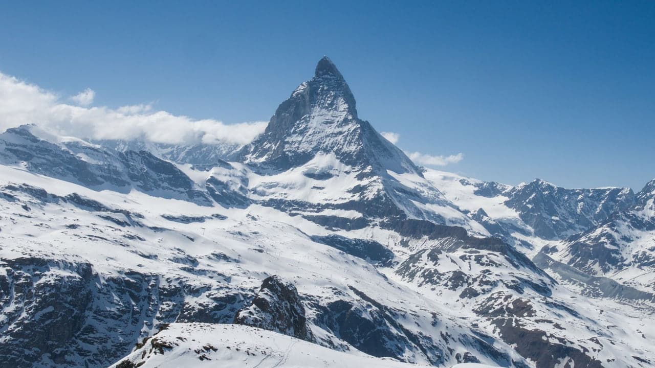 The Matterhorn's pyramid peak above snow covered ridgelines under a clear sky